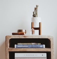books in brown wooden side table beside white wall