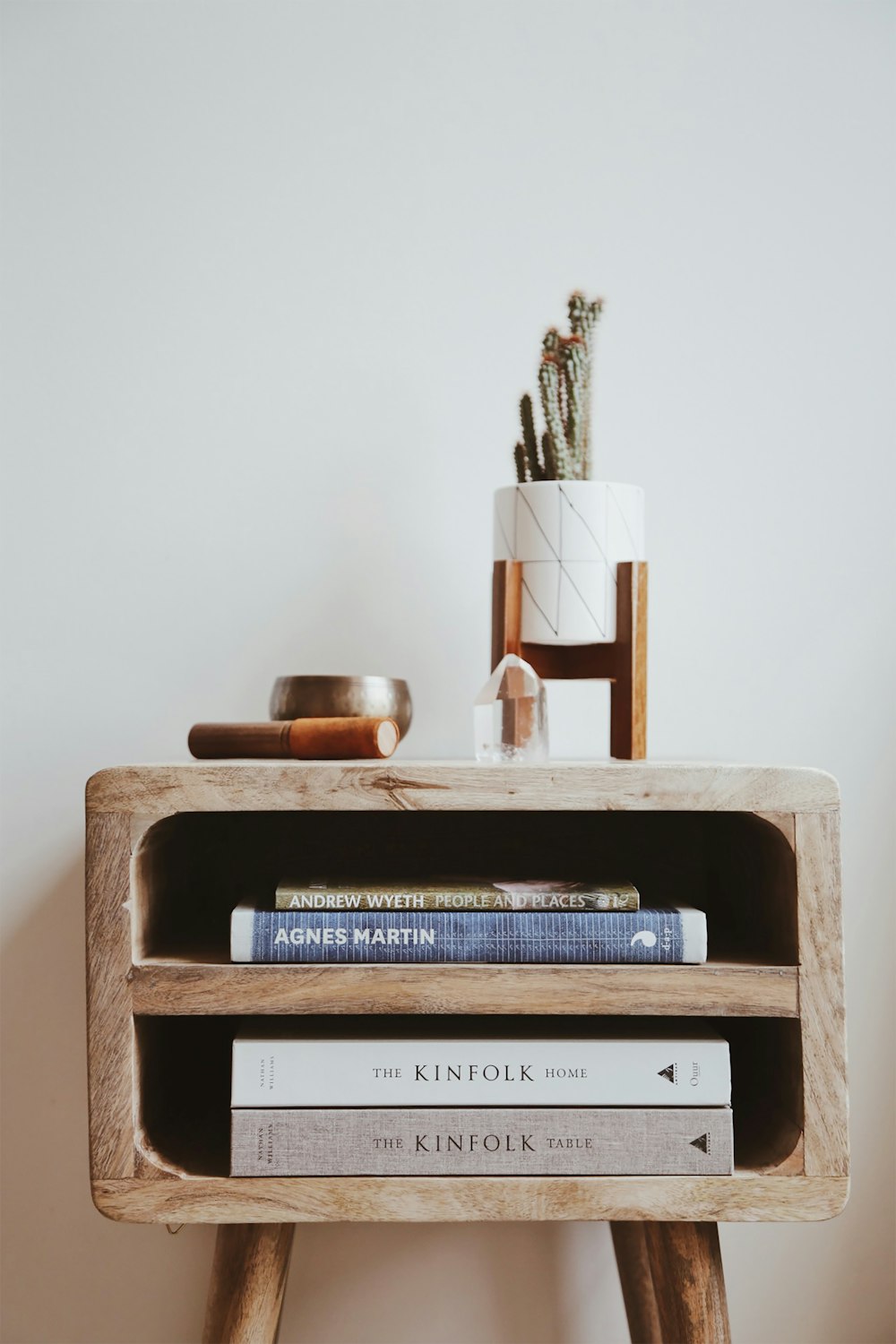 Libros en mesa auxiliar de madera marrón junto a la pared blanca