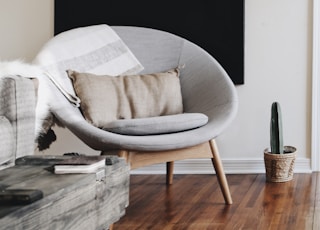 round grey moon chair with brown pillow on top