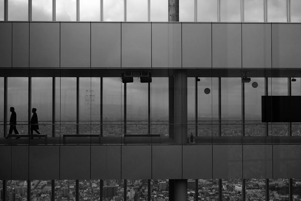 Photographie en niveaux de gris de deux hommes à l’intérieur d’un bâtiment