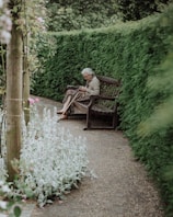 An elderly person enjoying a peaceful walk in a sunny garden.