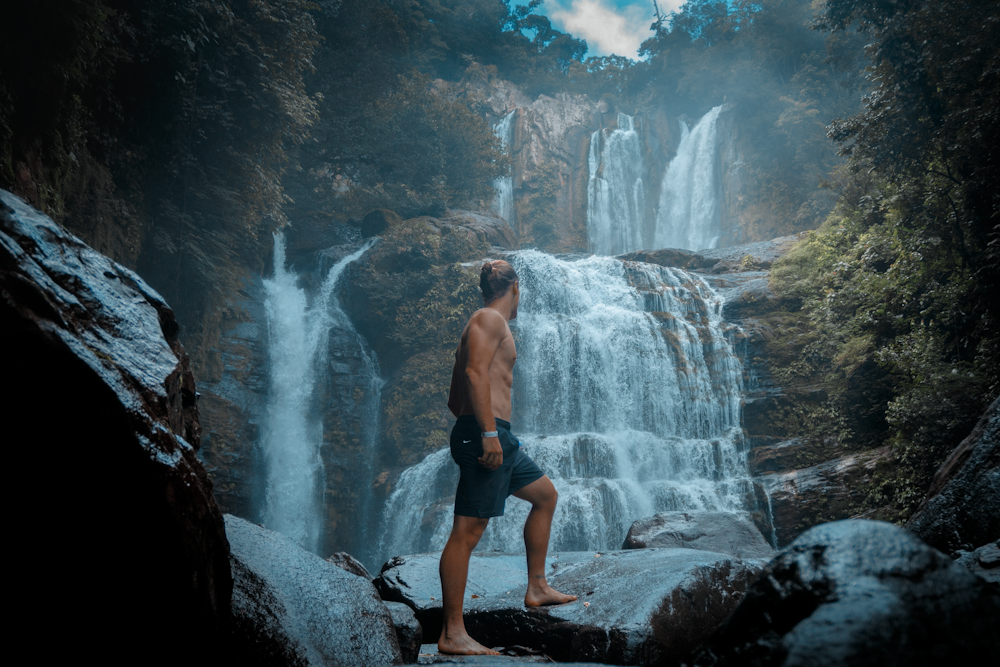 man standing near waterfalls