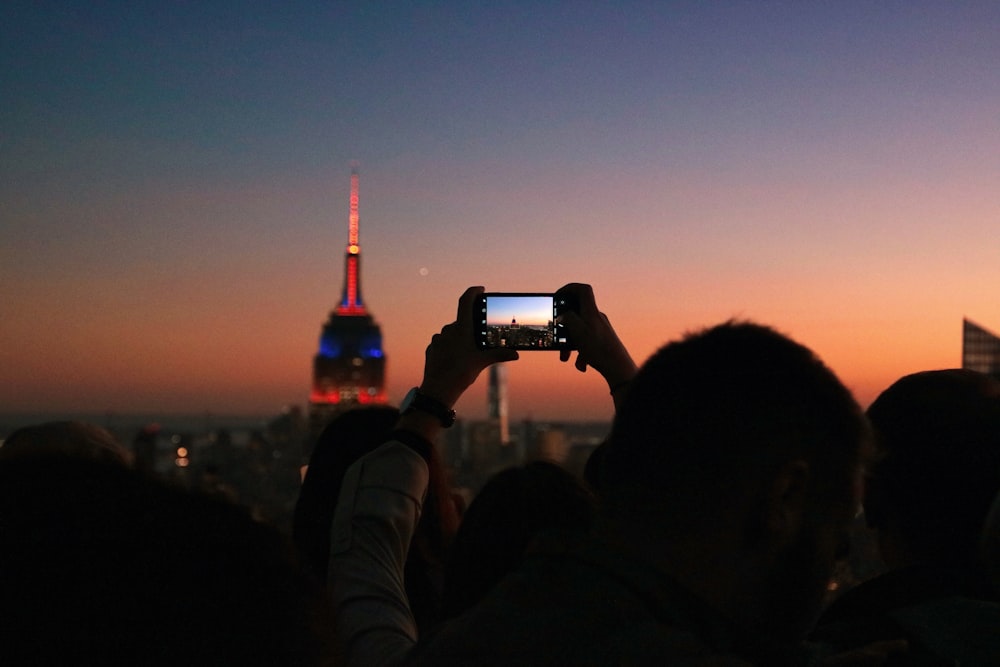 silhouette photo of man taking photo the lighted tower