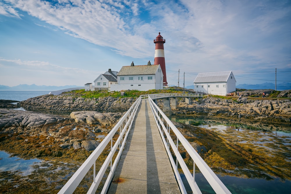 photo of suspension bridge towards into lighthouse during daytime