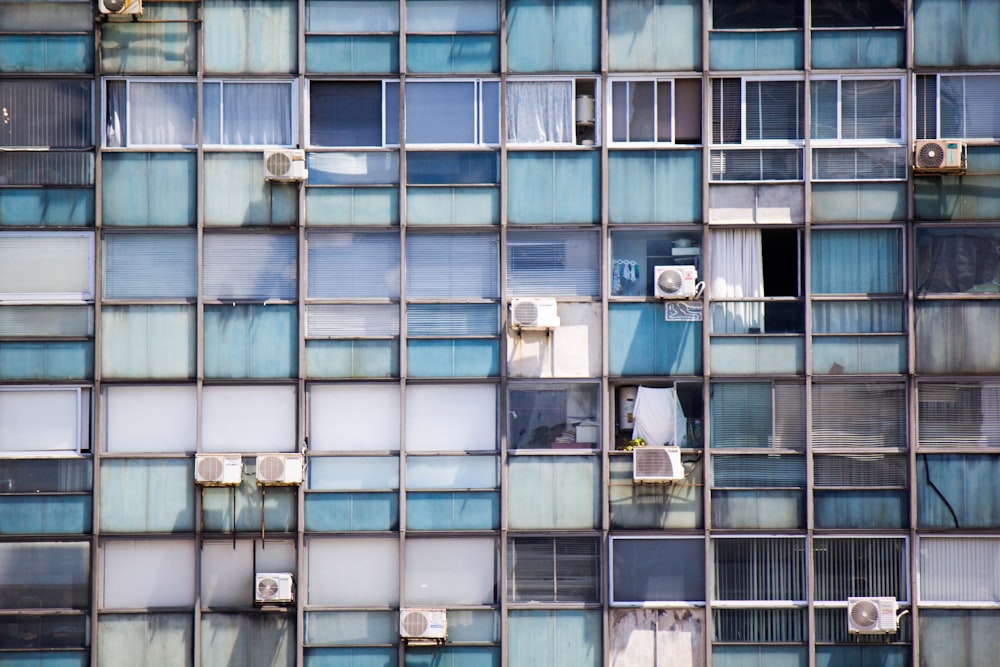 Edificio pintado de azul con aires acondicionados tipo ventana