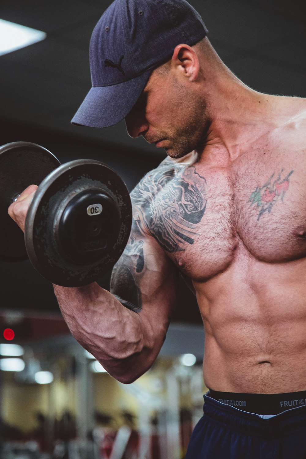 topless man holding black dumbell on right hand