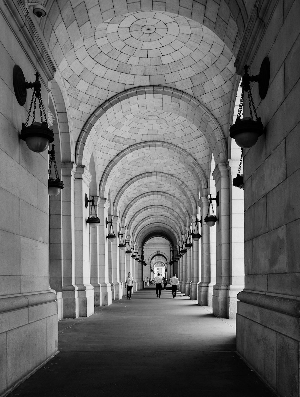 grayscale photo of people walking on building interior