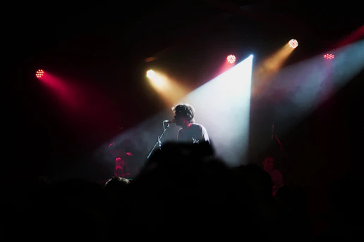 A confident child speaking passionately on stage with colorful lights and an engaged audience.