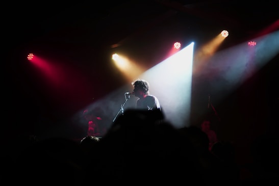 A lively comedy club stage with a spotlight on a comedian holding a microphone, audience laughing in the background.