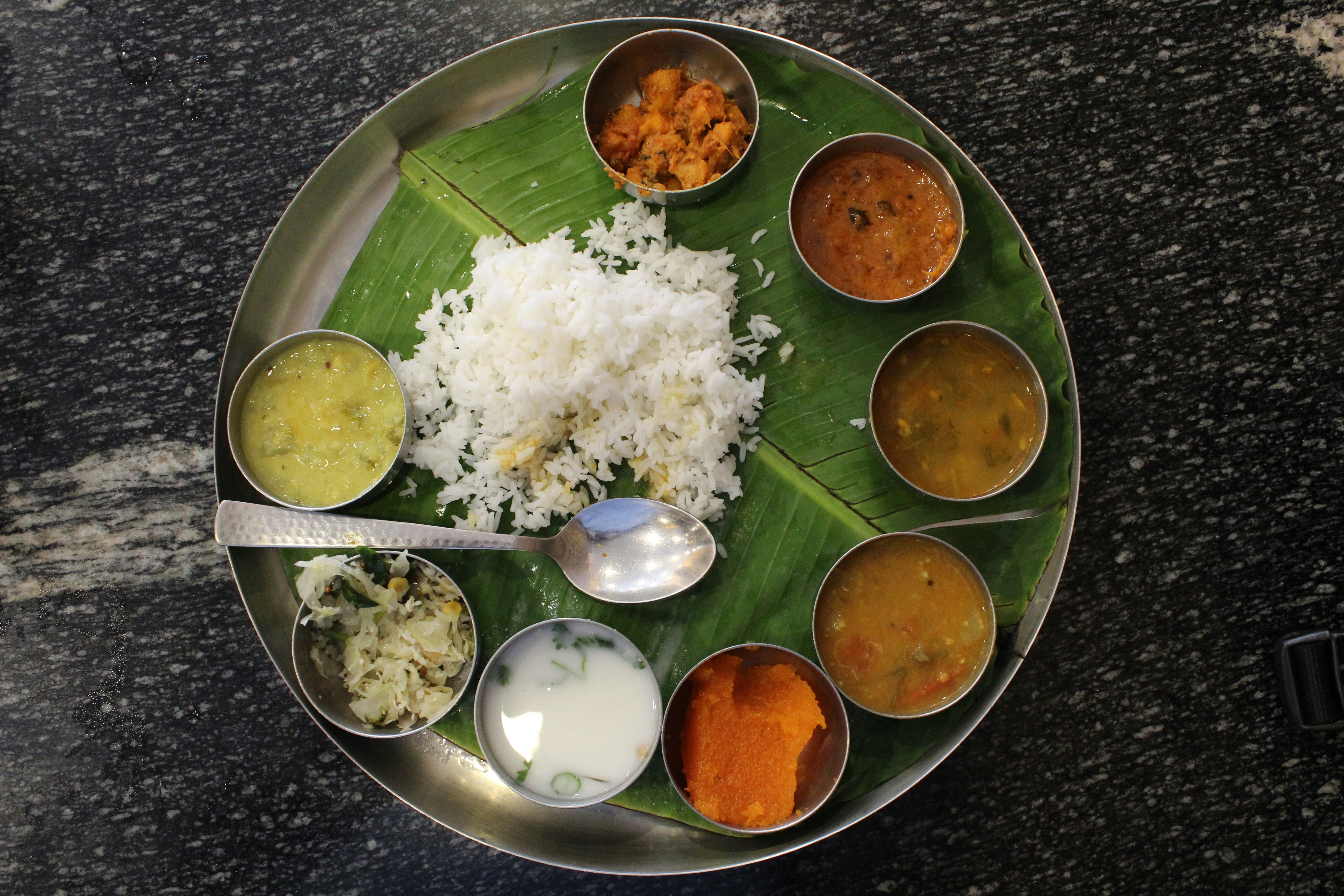 Colorful Indian thali with rice, dal, curries and bread on banana leaf