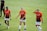 Three female soccer players walk across a grassy field wearing orange and black team jerseys with the logo 'DASH' and sponsor 'BBVA Compass'. They appear to be focused, possibly after a training session or match.