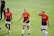 Three female soccer players walk across a grassy field wearing orange and black team jerseys with the logo 'DASH' and sponsor 'BBVA Compass'. They appear to be focused, possibly after a training session or match.