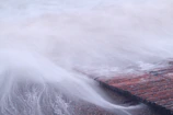 A long exposure shot capturing the swirling water around weathered wooden pilings.