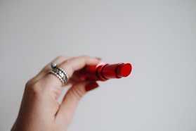 person holding red lipstick