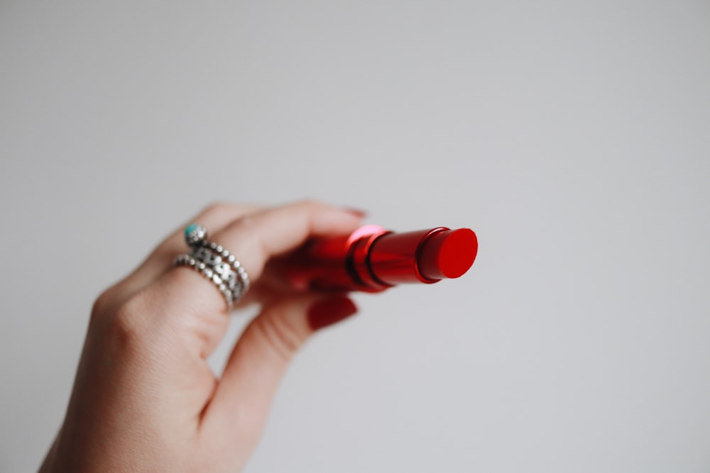 person holding red lipstick