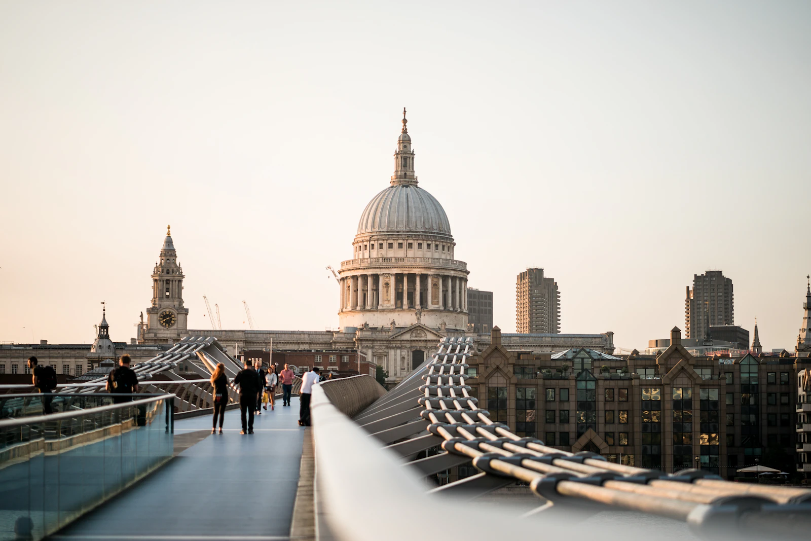 Travel photograph: People walking Millennium Bridge towards the dome of St Paul's Cathedral in late light.