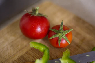 Close-up of a vibrant, ripe tomato on a wooden cutting board, highlighting fresh local produce
