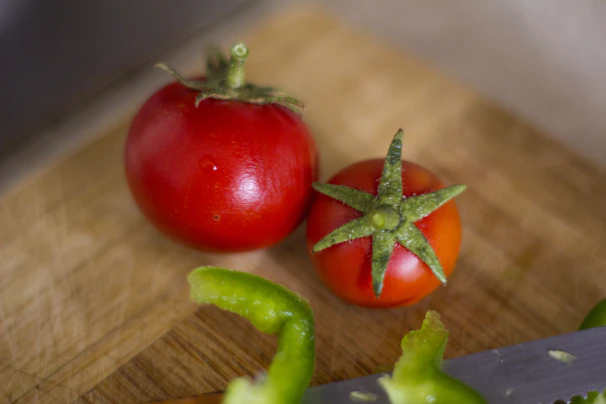 Close-up of a vibrant, ripe tomato on a wooden cutting board, highlighting fresh local produce