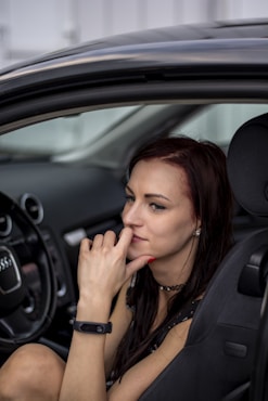 selective focus photo of woman sitting front of vehicle steering wheel