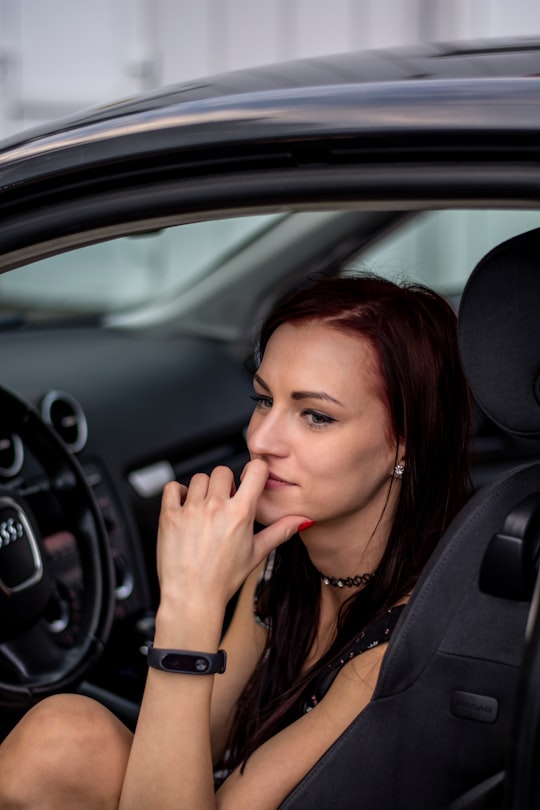 selective focus photo of woman sitting front of vehicle steering wheel in Kaunas Lithuania