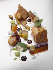 A beautifully plated dish of seared scallops garnished with microgreens and a drizzle of citrus sauce.