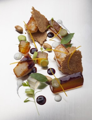 A beautifully plated dish of seared scallops garnished with microgreens and a drizzle of citrus sauce.