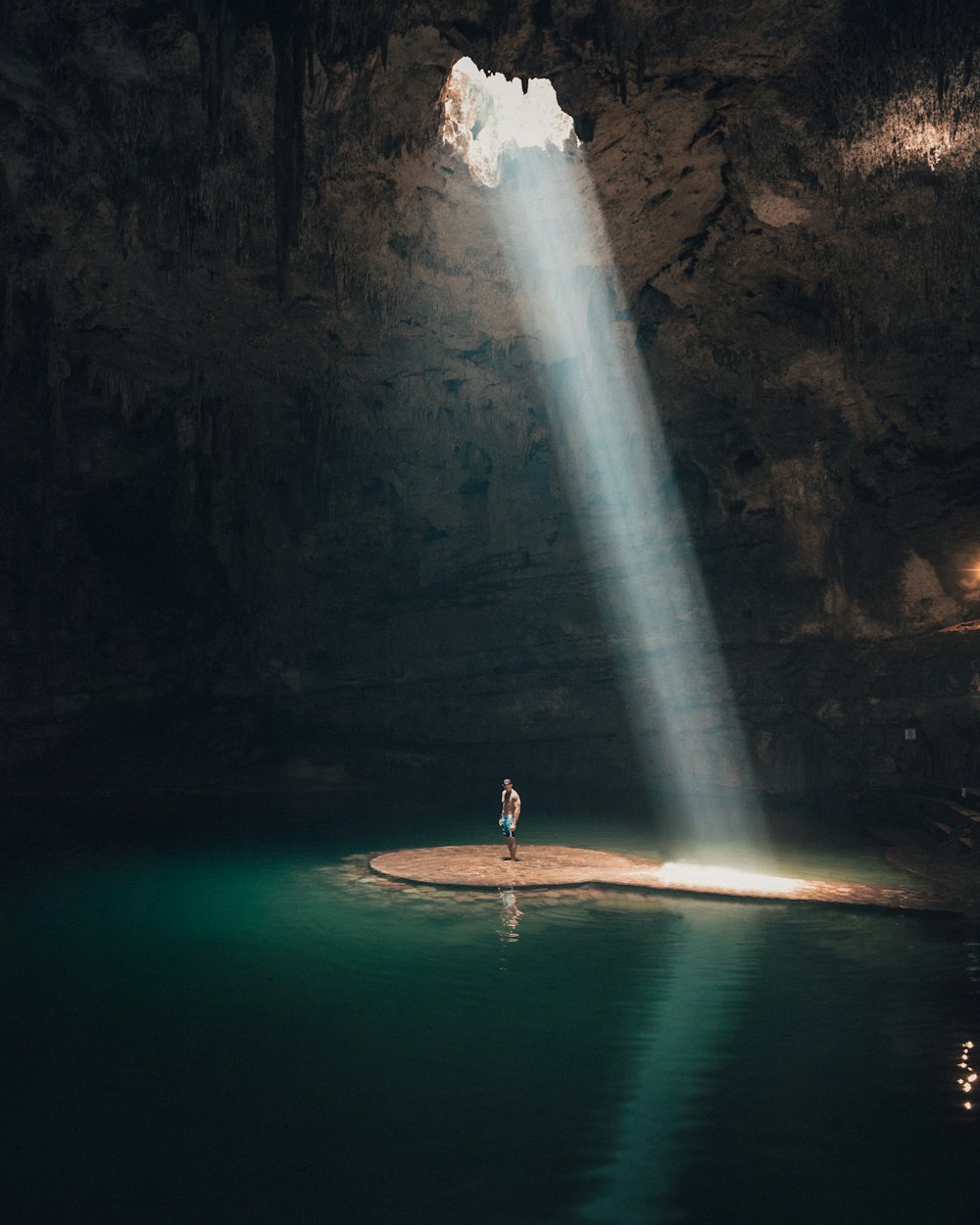 水に囲まれた洞窟に立つ男性の写真