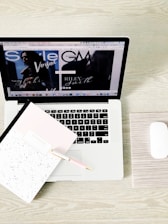 An open laptop displaying a tax lien auction website with a notepad and pen beside it.