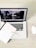 A laptop displaying a webpage with various tabs open. In front of the laptop, there is a closed notebook with a speckled cover and a pink pen resting on it. A white wireless mouse is positioned on the right side of the laptop, all set on a light wooden surface.