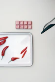 An elegant butter piece with chili pepper accents displayed on a sleek white surface.