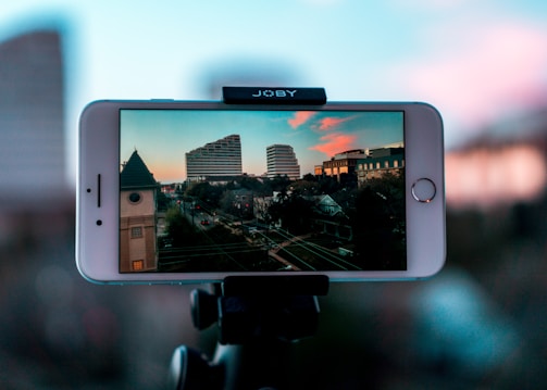 Close-up of a smartphone camera lens capturing a vibrant cityscape at sunset.