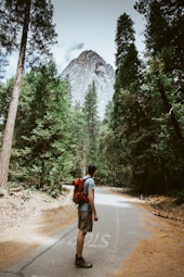 man carrying red camping backpack near mountain