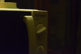 A close-up of a microwave oven being serviced with tools.