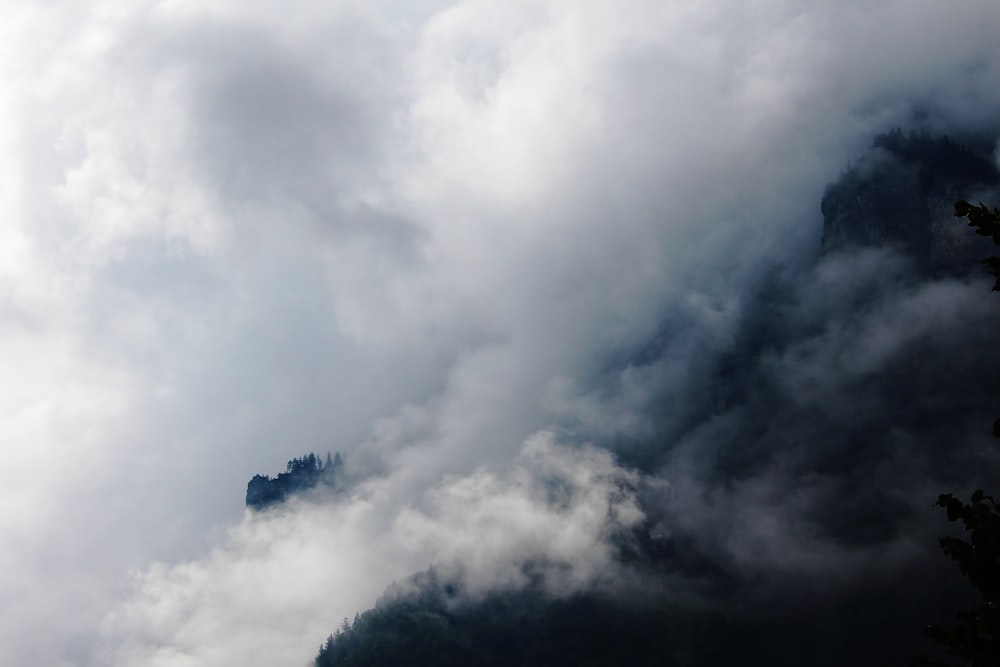 a very tall mountain covered in clouds and trees