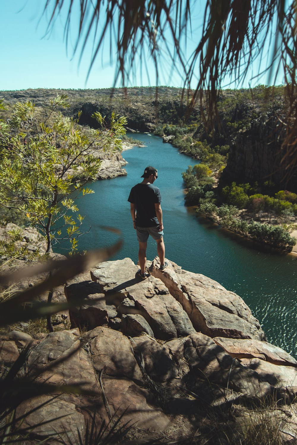 man standing on a cliff overlooking land and river