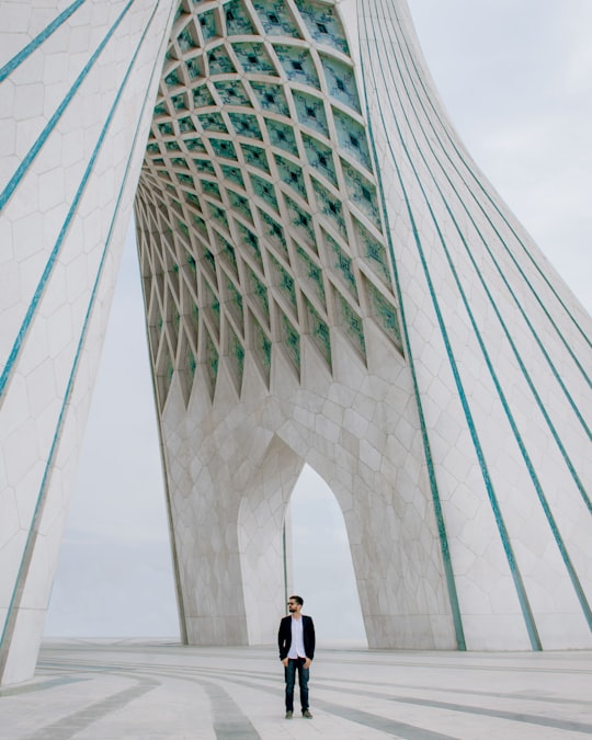 man standing under arch building in Azadi Tower Iran
