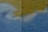 A textured wall with a combination of faint blue and yellow paint. There is a vertical crack running through the middle of the wall. The paint appears to have been applied unevenly, with some areas blending together.
