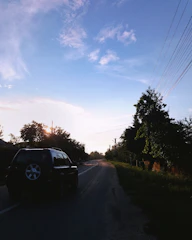 A tow truck helping a stranded car on a quiet roadside at sunset.