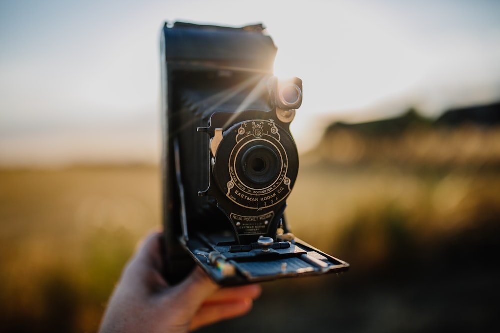 person holding black folding camera