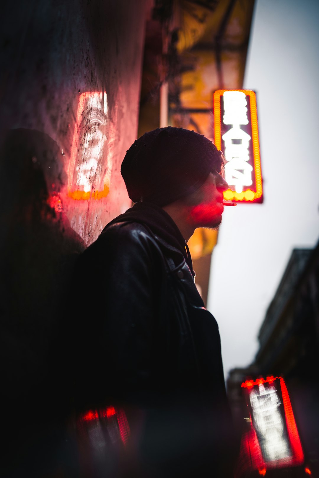 man leaning on wall under neon sign