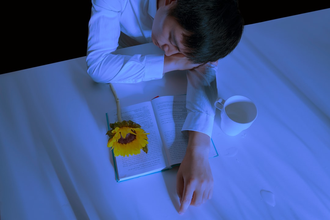 man in white dress shirt leaning on table beside book and mug