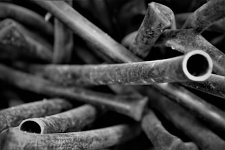 Close-up view of tangled, hollow cylindrical structures with a rough texture, resembling abstract forms in grayscale.