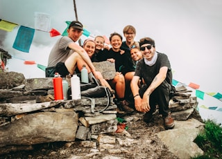 group picture of men and women on hill at daytime