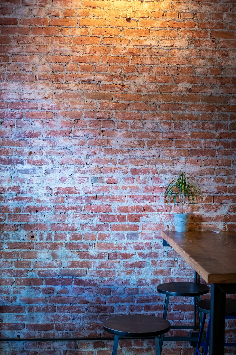 Table à manger en bois marron à côté d’un mur de briques brunes