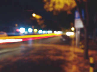 An urban night scene with glowing streetlights and blurred motion of passing cars