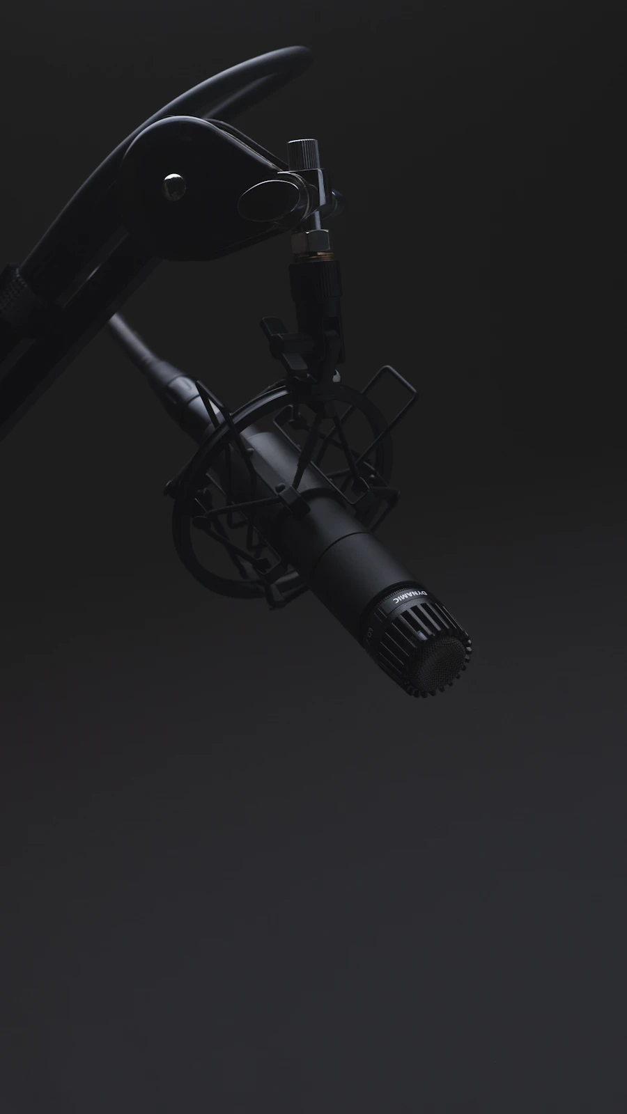 A condenser microphone lit in a darkened recording room