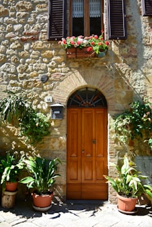 Close-up of a traditional stone barn with wooden doors and flowering plants.