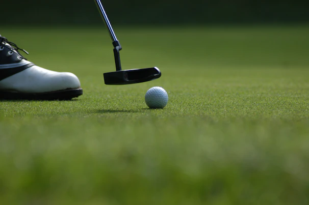 Hands gripping a polished putter, ready to make a precise stroke on a smooth green.