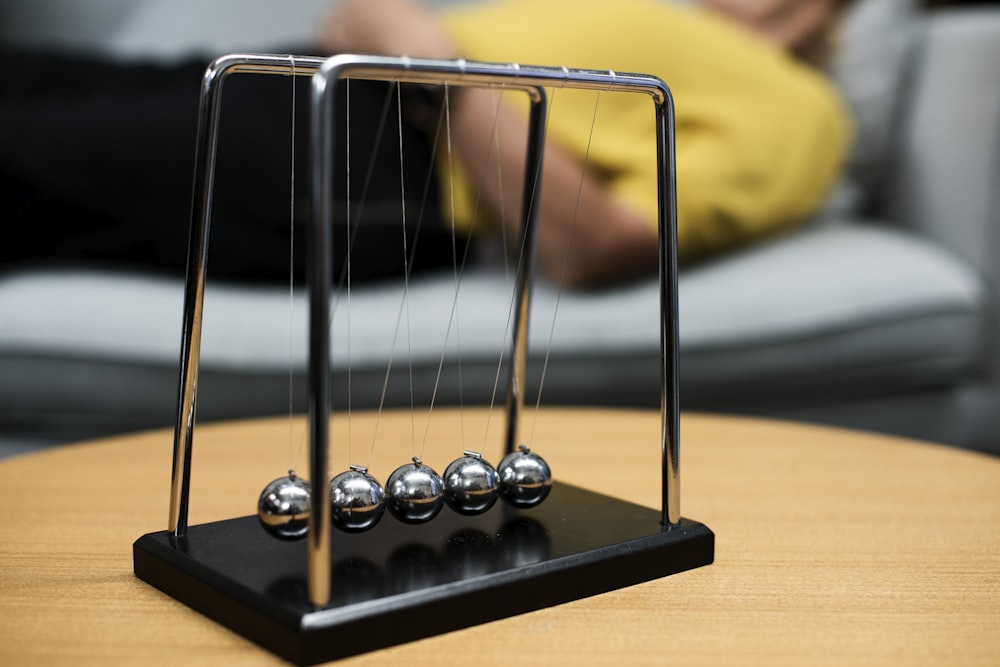 selective focus photography of gray Newton's Cradle on brown wooden table