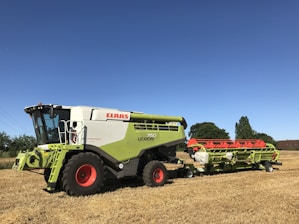 Photo of a Mahindra combine harvester in a golden wheat field under a clear blue sky.